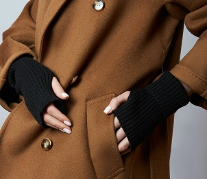 Close-up van een bruine jas met de handen in de zakken en zwarte mouwen, een stijlvol detail voor de herfstmode.