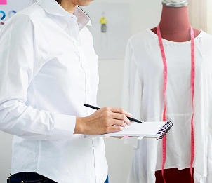 Een modeontwerper schetst en neemt maten op een paspop, en het ontwerp- en naaiproces van kleding vindt plaats in de studio.